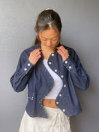 Model wearing the Say the Label Wave Denim Jacket open over a white top, styled with white trousers