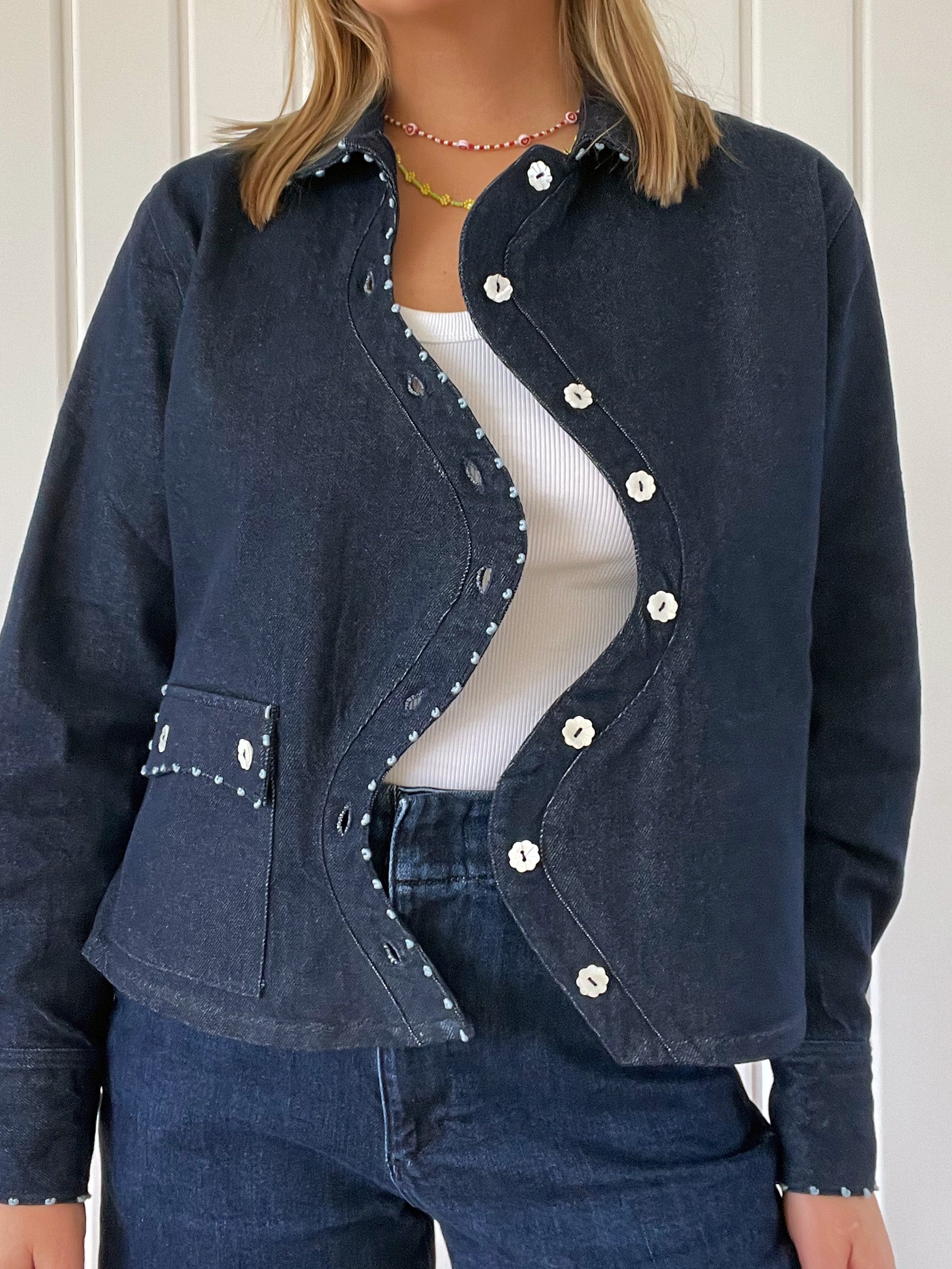 Close-up of the Say the Label Wave Denim Jacket showing the curved placket and mother-of-pearl buttons