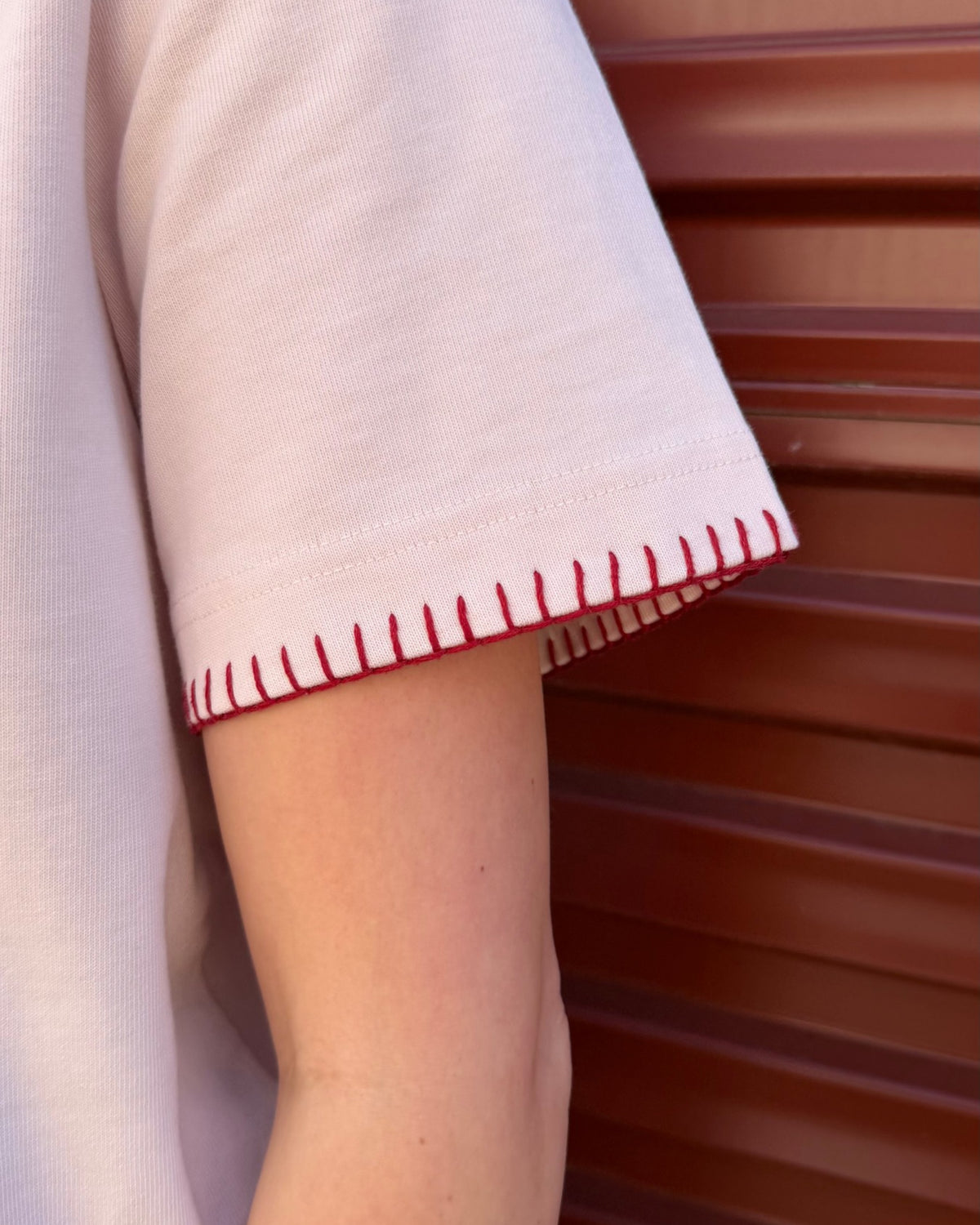 Close-up of the hand-stitched blanket-stitch cuff on the Signature Tee in blush pink